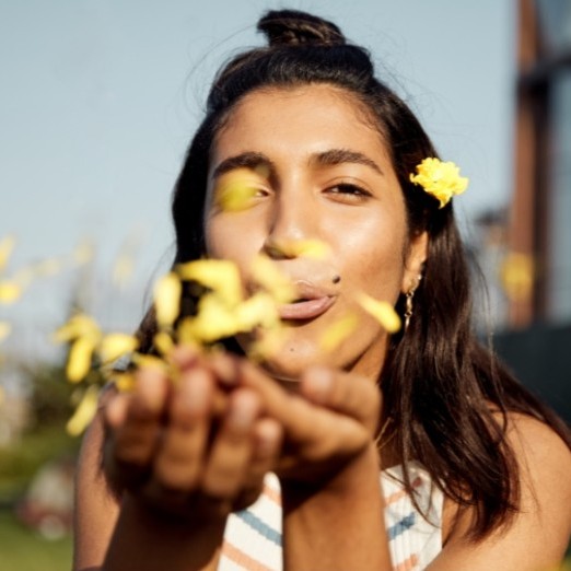 Woman blowing flower petals into the air