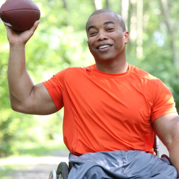 A man using a wheelchair and throwing a football