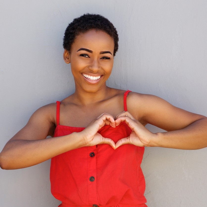Woman smiling and making a heart shape with her hands