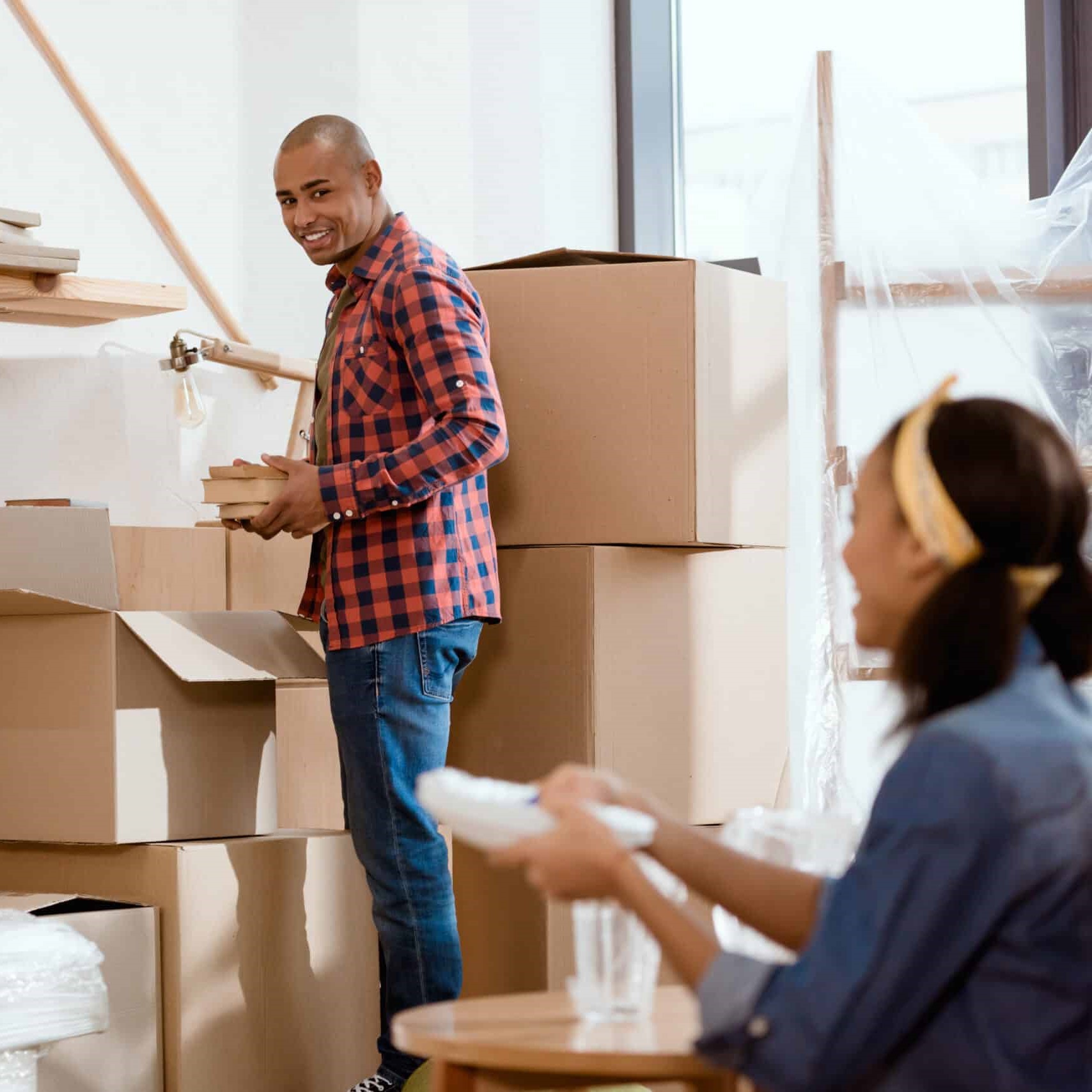 Man and woman unpacking boxes in a sunny room.