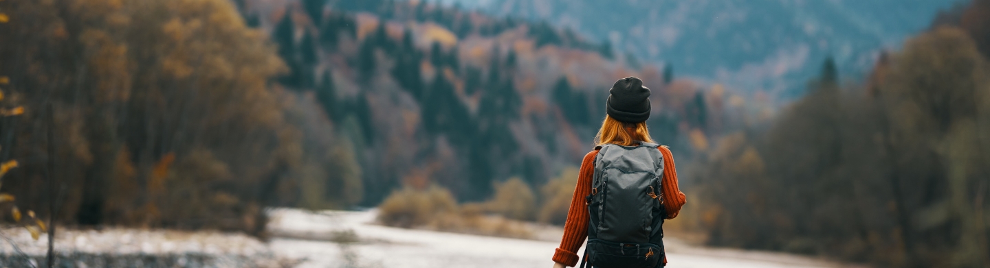 Female hiker wearing an orange sweater and carrying a backpack